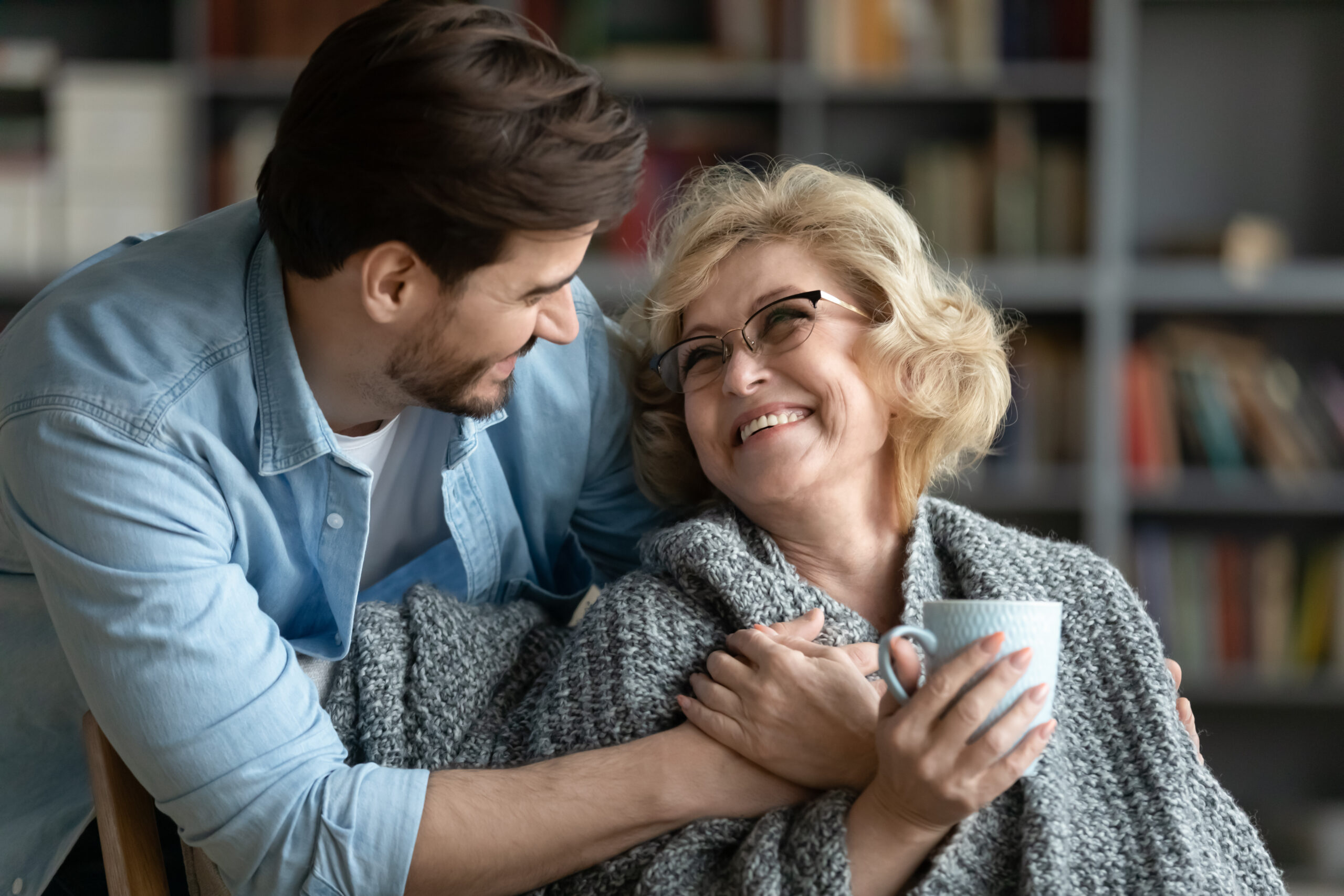 Smiling older woman holding a cup while embraced by a man in a cozy indoor setting, symbolizing comfort, trust, and compassionate eye care for all ages – otsego eye doctor
