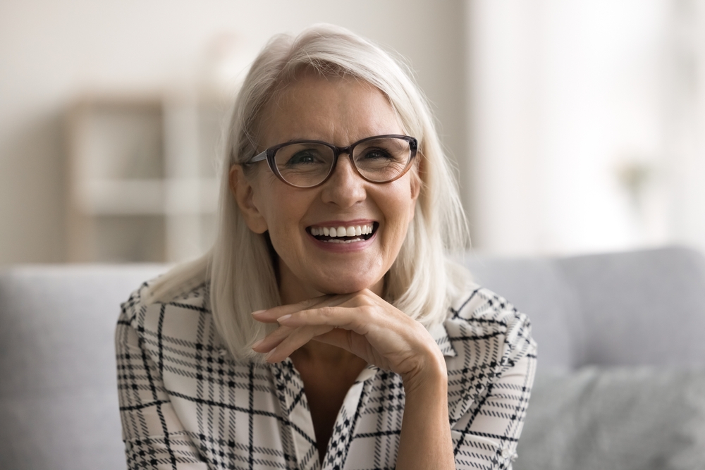 Happy older woman wearing eyeglasses and smiling in a bright indoor setting, symbolizing clarity, comfort, and trusted eyewear solutions – glasses in plymouth