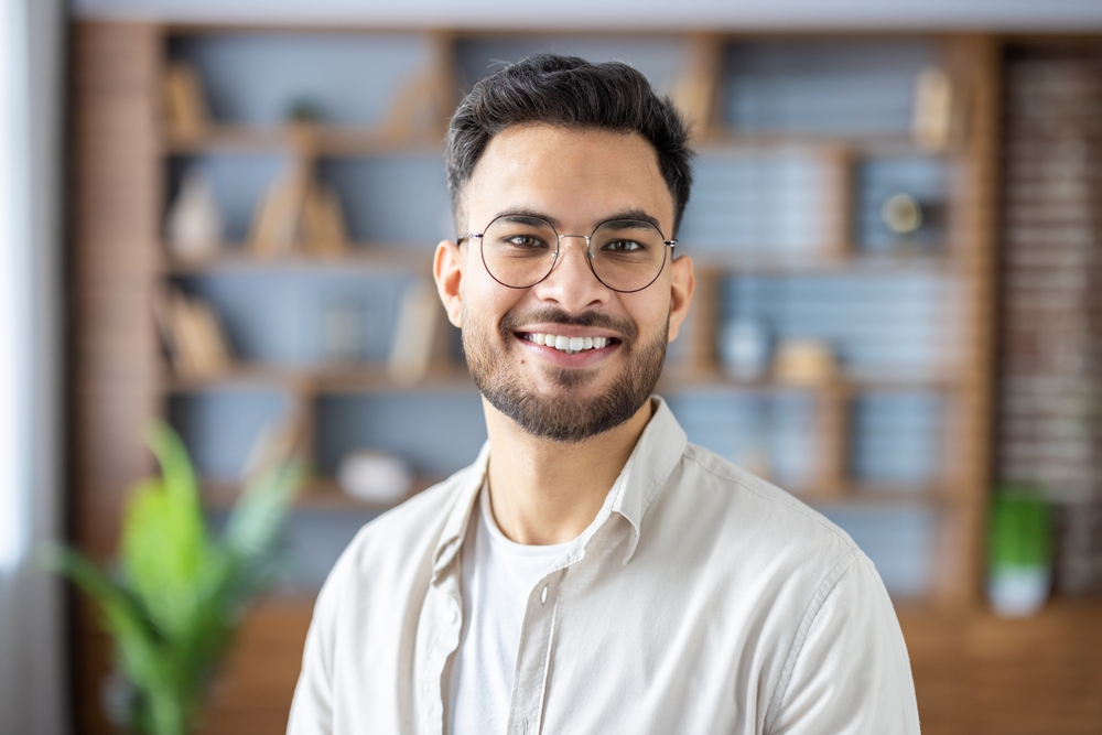 Smiling man wearing modern eyeglasses in a bright indoor setting, representing clear vision, comfort, and contemporary eyewear styles – glasses in plymouth