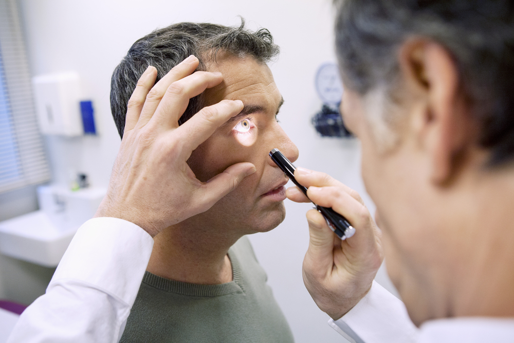 Eye care professional performing a close-up eye examination using a handheld light, representing thorough vision screening and medical eye care – eye exam plymouth